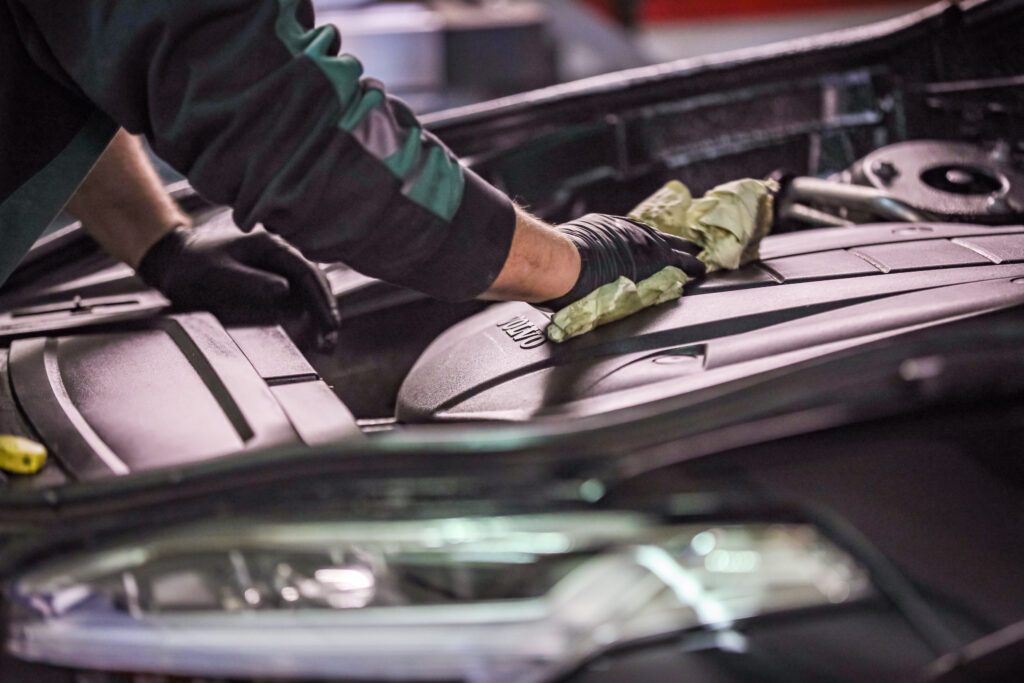 Bilde av Carfix-mekaniker som holder på å tørke av deksel over motor.