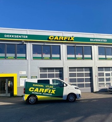 Bilde av utsiden av Carfix Søgne, med Carfix-profilering. Bygget er i 2 etasjer, og viser 3 verkstedsporter. Foran bygget står en varebil med Carfix-profilering.
