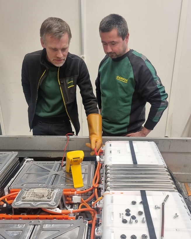 Bilde av to Carfix-ansatte som holder på å reparere et elbilbatteri